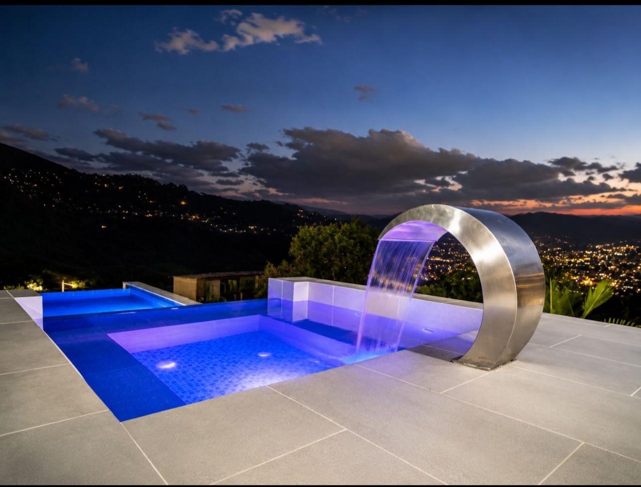 Piscina infinita con cascada al atardecer